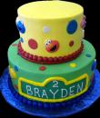 Sesame Street 2nd Birthday Cake. Yellow and green butercream iced, round 2 tiers decorated with circles, dots and the faces of elmo, cookie monster and big bird. Everything on this cake is edible. (Serves 28-55 party slices.) 