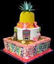 Hawaiian Birthday Cake,  White and yellow buttercream iced,   3 tiers decorated with tiki mask, palm trees, flamingos, seashells and starfish.  Wrapped with an edible floral print and topped with a whole pineapple complete with a Hawaiian flower lei. Everything on this cake is EDIBLE.  (Serves 78-135 party slices)