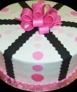 Pink Ribbon Black Bow Birthday Cake. White buttercream iced, round decorated with pink circles, black ribbons and a pink bow. Everything on this cake is edible. (Serves 8-80 party slices.) 