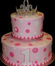 Rhinestone Tiara 1st Birthday Cake. Pink buttercream iced, round 2 tiers decorated with circles, dots and a rhinestone tiara. Everything on this cake is edible except the tiara. (Rhinestone tiara provided by client) (Serves 28-55 party slices.) 