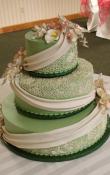 Olive Green buttercream iced,  3 tier round wedding cake decorated with Candlelight drapes and piped alencon lace . Gumpaste as the topper.  (This cake can serve receptions with 90-220 expected guests)