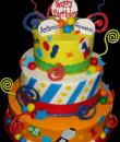 Gumball Machine 1st Birthday cake, Yellow, White and Orange Buttercream iced, 3 tiers adorned with gumball candy, Chocolate swirls, Fondant balloon cutouts, ribbons and stripes. 
